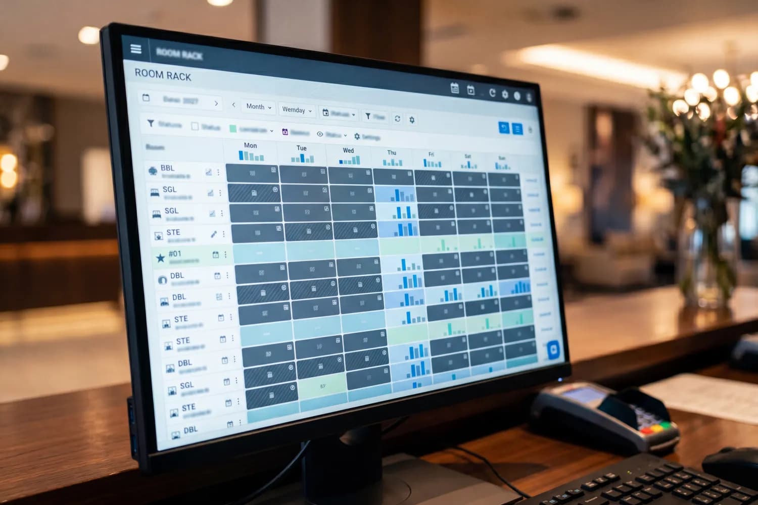 A hotel reception desk with a monitor showing an abstract room-inventory grid and a channel-sync panel with placeholder bars — an illustration of a single window for availability management